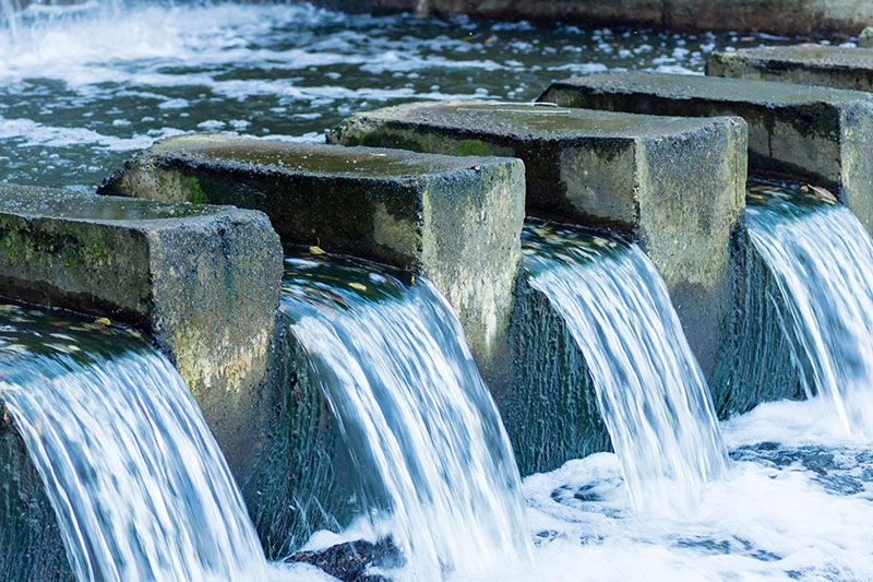 The water stream flows through a concrete dam